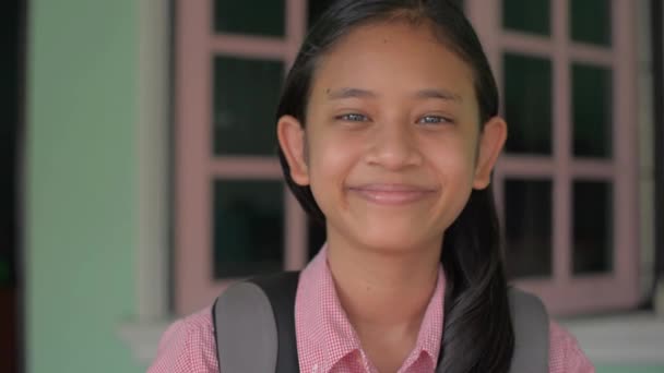 亚洲长头发可爱的高中女生穿着校服 背着背包微笑着看着相机 在上学前在她家门前摆姿势的快乐的泰国少女的画像 — 图库视频影像