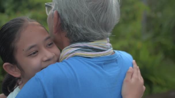 快乐的亚洲可爱的孙女站在院子里抱着灰白的祖父 用爱心拥抱年迈的祖父母 团结在一起 两代人的粘合 — 图库视频影像