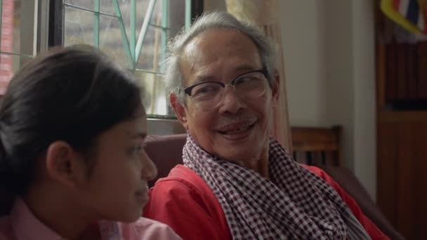 有趣的老灰发祖父坐在客厅里和他快乐的孙女聊着天 两代人在一个家庭的结合 老年人与儿童的关系 — 图库视频影像