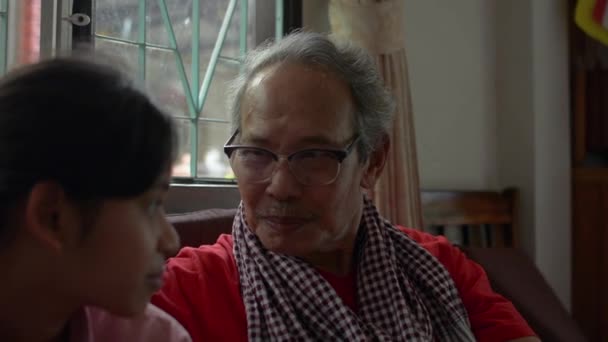 快乐的亚洲老爷爷戴着眼镜 坐在客厅里和他可爱的小孙女聊天 两代家庭中的结合关系 — 图库视频影像