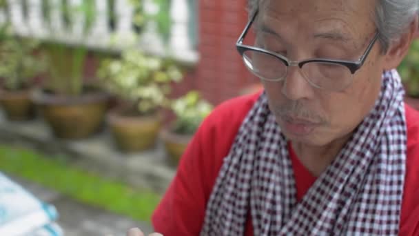 当她的祖父坐在家里用手机时 亚洲少年孙女出现了 并从后面接近她的祖父 在一个家庭里结合两代人 — 图库视频影像