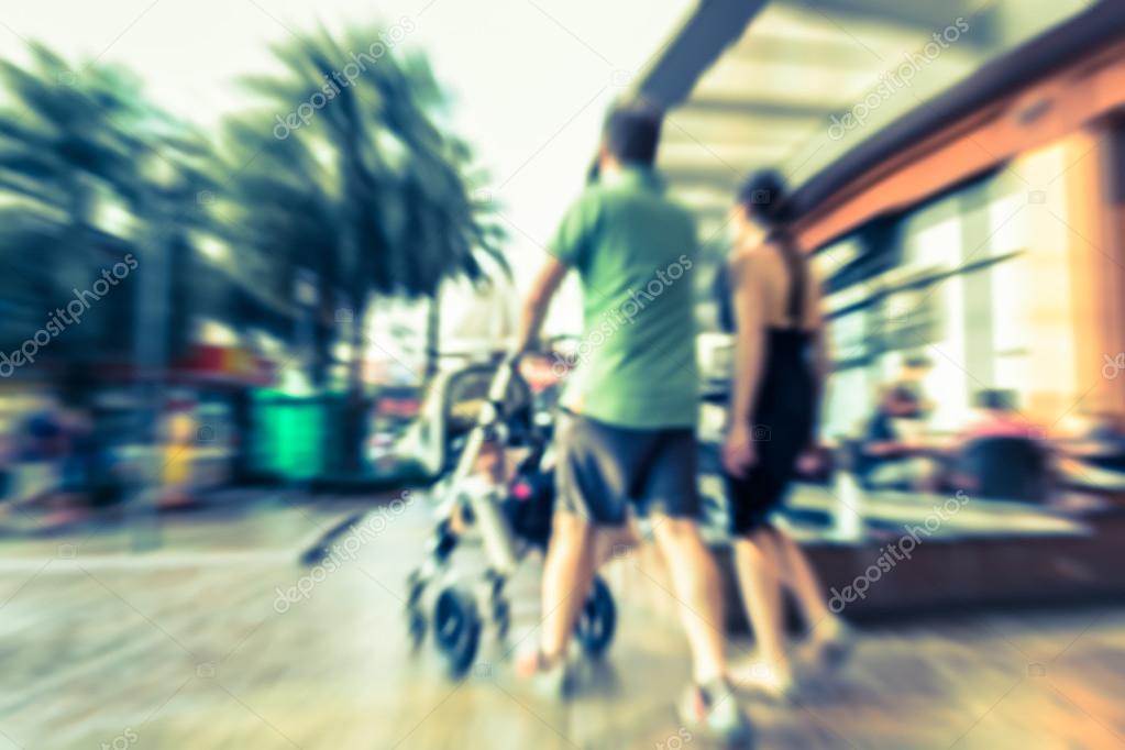 Motion blurred couple with baby stroller in the shopping center