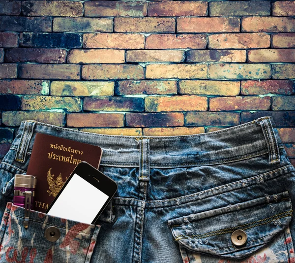 Голубые джинсы с мобильным телефоном, паспортом и фонариком в кармане — стоковое фото