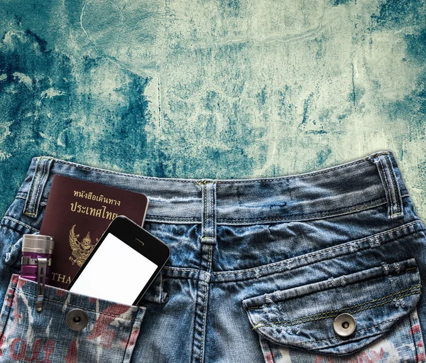 Голубые джинсы с мобильным телефоном, фонариком и паспортом в кармане — стоковое фото