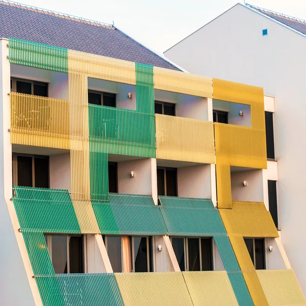 Pattern of hotel room balconies in modern building with warm sunset light falling on facade