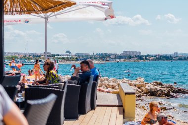 Zadar, Hırvatistan - 28 Temmuz 2015: Turist ve çeşitli Deniz kenarındaki barda oturan misafirler ve Zadar içinde güneşin tadını.