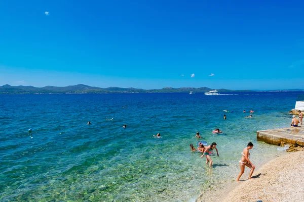 ZADAR, CROAZIA - 28 LUGLIO 2015: I turisti nuotano nel mare Adriatico vicino a Zara nella giornata di sole . — Foto Stock