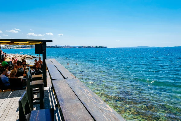 Zadar, Kroatië - 28 juli 2015: Toeristen en diverse gasten zitten aan de bar aan zee en genieten van de zon in Zadar. — Stockfoto