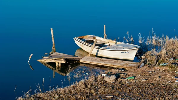 Old fishing boat on the shore. Polluted environment and water — Stock Photo, Image