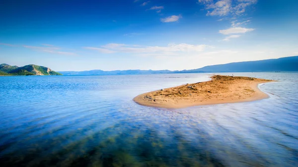 Lone small sandy island in the middle of blue sea — Stock Photo, Image