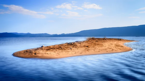 Piccola isola di sabbia solitaria in mezzo al mare blu — Foto Stock