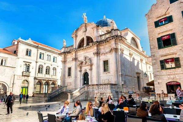DUBROVNIK, CROATIA - APRIL 10: Tourists enjoy the terraces of restaurants in the old town of Dubrovnik in front of the Church of St. Blaise on April 10, 2015. — Stock Photo, Image