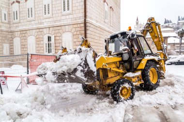 METKOVIC, CROATIA - FEBRUARY 4: Excavator cleans the streets of large amounts of snow in Metkovic, Croatia on February 4, 2012. clipart