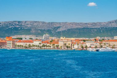 BÖLÜM, CROATIA, 16 Temmuz 2019: Güneşli bir yaz gününde Diocletian Sarayı, palmiye ağaçları ve Jadrolinija feribotlarıyla Split Riva 'nın panoramik manzarası