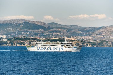 Split, Hırvatistan, 16 Temmuz 2019: Jadrolinija feribotu Marjan, arka planda Dalmaçya kıyı şeridi ve Mosor dağlarıyla Adriyatik Denizi 'ne yelken açıyor