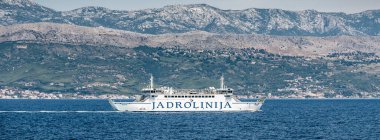 Split, Hırvatistan, 16 Temmuz 2019: Jadrolinija feribotu Marjan, arka planda Dalmaçya kıyı şeridi ve Mosor dağlarıyla Adriyatik Denizi 'ne yelken açıyor