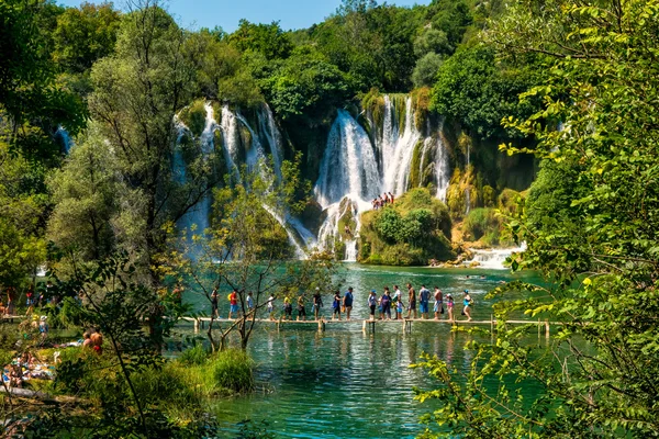 LJUBUSKI, BOSNIA Y HERZEGOVINA - 10 DE AGOSTO DE 2014: Muchos turistas visitan las cascadas de Kravice en el río Trebizat cerca de Ljubuski en Bosnia y Herzegovina . —  Fotos de Stock