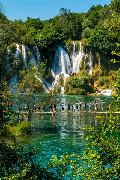 LJUBUSKI, BOSNIA Y HERZEGOVINA - 10 DE AGOSTO DE 2014: Muchos turistas visitan las cascadas de Kravice en el río Trebizat cerca de Ljubuski en Bosnia y Herzegovina . —  Fotos de Stock