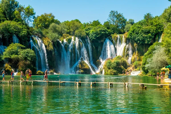 LJUBUSKI, BOSNIA Y HERZEGOVINA - 10 DE AGOSTO DE 2014: Muchos turistas visitan las cascadas de Kravice en el río Trebizat cerca de Ljubuski en Bosnia y Herzegovina . —  Fotos de Stock