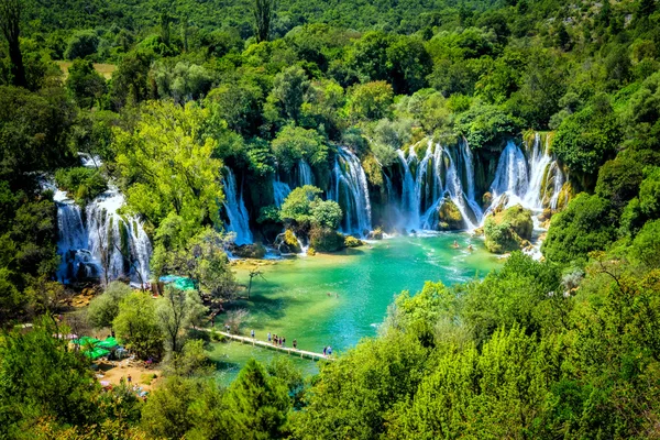 LJUBUSKI, BOSNIA Y HERZEGOVINA - 10 DE AGOSTO DE 2014: Muchos turistas visitan las cascadas de Kravice en el río Trebizat cerca de Ljubuski en Bosnia y Herzegovina . —  Fotos de Stock