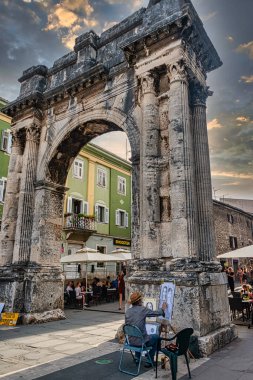 Hırvatistan 'ın Pula kentindeki Sergii Zafer Kemeri' nin önünde ressam bulunuyor