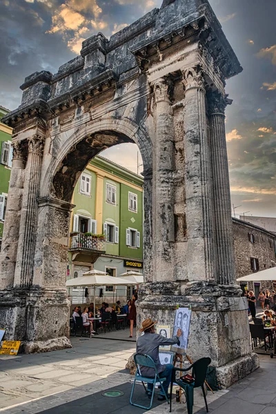 Hırvatistan 'ın Pula kentindeki Sergii Zafer Kemeri' nin önünde ressam bulunuyor