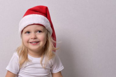 Noel Baba şapkalı küçük bir çocuk gülümsüyor.