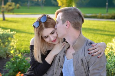 Genç bir çift bankta oturuyor ve gülümsüyor.