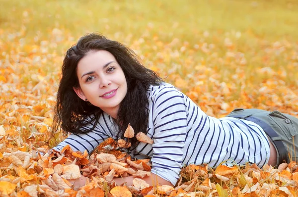 少女は木の黄色の秋の葉に横たわっている — ストック写真
