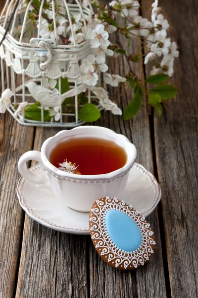 Чашка чая и пасхальное печенье на деревянном фоне — стоковое фото