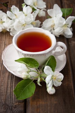 Çiçekler ve ahşap arka plan üzerinde çay bardağı