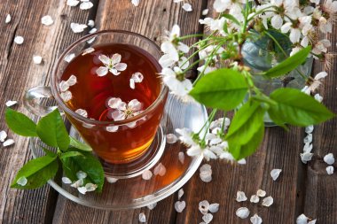 Çiçekler ve ahşap arka plan üzerinde çay bardağı