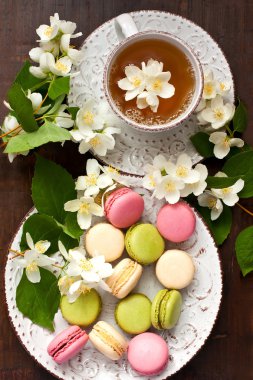 Lezzetli Fransız macarons ve çay Kupası ahşap arka plan, üstten görünüm
