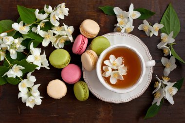 Lezzetli Fransız macarons ve çay Kupası ahşap arka plan, üstten görünüm