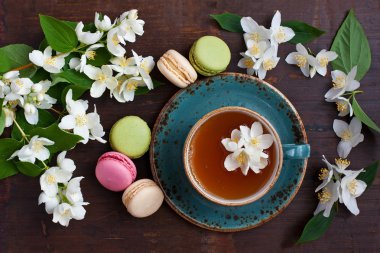 Lezzetli Fransız macarons ve çay Kupası ahşap arka plan, üstten görünüm