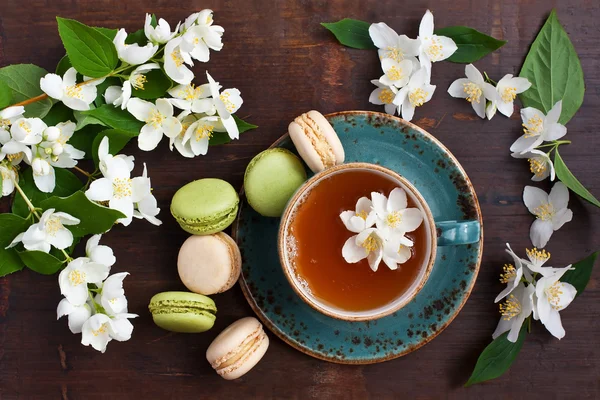 Chutné francouzské macarons a tea cup na dřevěné pozadí, pohled shora — Stock fotografie