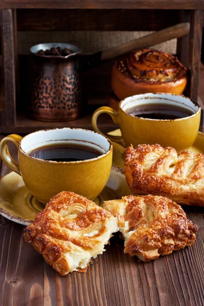 Koffiekopje met broodjes op tafel — Stockfoto