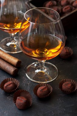 Bir bardak güçlü alkolik brendi ya da konyak ve koyu arkaplanda bir kutu çikolata şekeri içer. Seçici odak