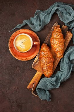 Koyu arka planda seramik fincan kahve espresso ile taze pişmiş farklı kruvasan. Düz yat, boşluğu kopyala