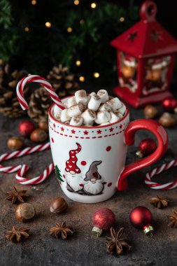 Bir fincan kremalı sıcak çikolata, eritilmiş şekerlemeler ve Noel tatili için baston şekerler.