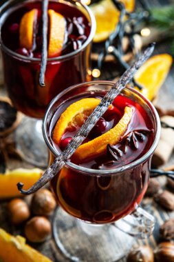 Noel sıcak kırmızı şarap ve ilave tarçın çubukları, anason yıldızları, yaban mersini ve portakallar cam içinde, sığ alan derinliğinde seçici odak 