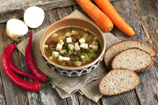 Een gezond vegetarisch bonesoep in kom op oude houten tafel — Stockfoto