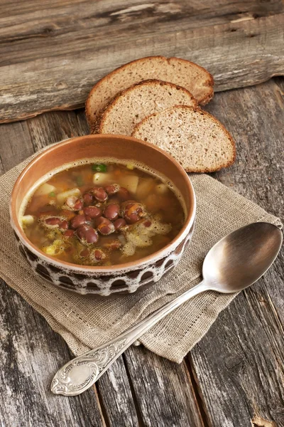 A healthy vegetarian bean soup in bowl on old wooden table — Stock Image A healthy vegetarian bean soup in bowl on old wooden table Stock Photo