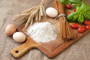 Pişmemiş makarna ve malzemeler ahşap tahta üzerinde