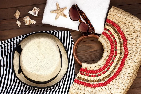 Sac de plage avec serviette, lunettes de soleil et chapeau sur fond en bois — Photo