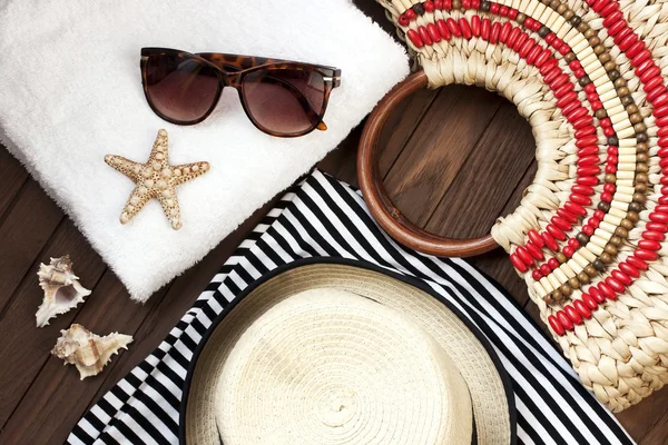 Bolsa de playa con toalla, gafas de sol y sombrero sobre fondo de madera — Foto de Stock