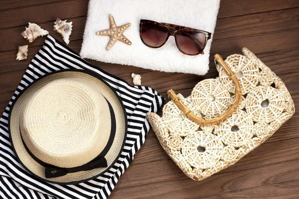 Torba plażowa z ręcznikiem, okulary przeciwsłoneczne i kapelusz na drewniane tła — Zdjęcie stockowe