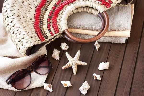 Bolsa de playa con toalla, gafas de sol y sombrero sobre fondo de madera — Foto de Stock