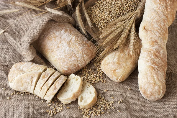 Ciabatta y baquette con orejas en la arpillera — Foto de Stock