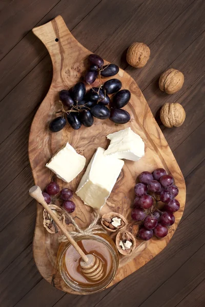 Formaggio, uva e miele su tavola di legno — Foto Stock